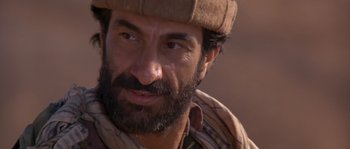 Movie still from “Rambo III” (1988), directed by Peter MacDonald – A person wearing a hat; Close Up shot, Over the shoulder angle