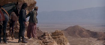 Movie still from “Rambo III” (1988), directed by Peter MacDonald – A man standing on top of a mountain looking out over the desert; Extreme Wide shot, Low angle