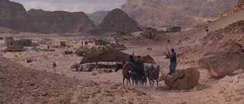 Movie still from “Rambo III” (1988), directed by Peter MacDonald – A group of people riding horses on a dirt road; Extreme Wide shot, High angle