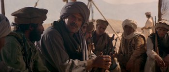 Movie still from “Rambo III” (1988), directed by Peter MacDonald – A group of men holding guns in their hands; Medium shot, Low angle