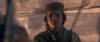 Movie still from “Rambo III” (1988), directed by Peter MacDonald – A young boy wearing a hat with a net on it; Close Up shot, Low angle