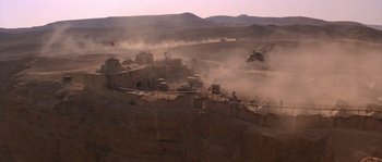 Movie still from “Rambo III” (1988), directed by Peter MacDonald – A helicopter flying over a desert area with sand blowing up; Extreme Wide shot, High angle