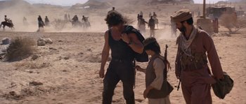 Movie still from “Rambo III” (1988), directed by Peter MacDonald – A man and a boy are walking through the desert; Wide shot, Over the shoulder angle