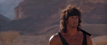 Movie still from “Rambo III” (1988), directed by Peter MacDonald – A person wearing a headband and a tank top; Close Up shot, Low angle
