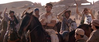 Movie still from “Rambo III” (1988), directed by Peter MacDonald – A group of men riding on the backs of horses; Medium shot, Over the shoulder angle