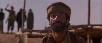 Movie still from “Rambo III” (1988), directed by Peter MacDonald – A man with a beard wearing a hat; Close Up shot, Low angle
