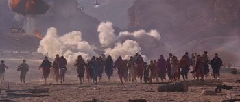 Movie still from “Rambo III” (1988), directed by Peter MacDonald – A group of people walking on top of a dirt field; Extreme Wide shot, High angle