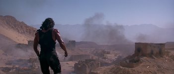 Movie still from “Rambo III” (1988), directed by Peter MacDonald – A man standing on top of a dirt hill; Wide shot, Low angle