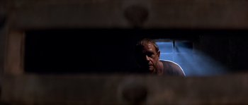 Movie still from “Rambo III” (1988), directed by Peter MacDonald – A man looking into a mirror in a room; Close Up shot, Low angle