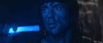 Movie still from “Rambo III” (1988), directed by Peter MacDonald – A man's face in a dark room; Close Up shot, Over the shoulder angle
