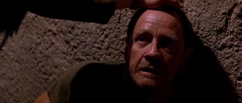 Movie still from “Rambo III” (1988), directed by Peter MacDonald – A person with a hand on his head; Close Up shot, Over the shoulder angle