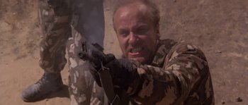 Movie still from “Rambo III” (1988), directed by Peter MacDonald – A man holding a gun in his hand; Close Up shot, Low angle