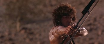 Movie still from “Rambo III” (1988), directed by Peter MacDonald – A person holding a bow and arrow; Close Up shot, Low angle