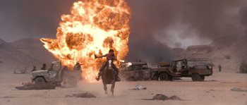 Movie still from “Rambo III” (1988), directed by Peter MacDonald – A man riding a horse in front of a huge explosion; Wide shot, Low angle
