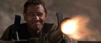 Movie still from “Rambo III” (1988), directed by Peter MacDonald – A man with a gun pointed at the camera; Close Up shot, Low angle