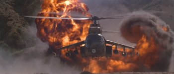 Movie still from “Rambo III” (1988), directed by Peter MacDonald – A military helicopter flying through the air with a lot of smoke behind it; Extreme Wide shot, Low angle