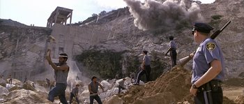 Movie still from “Rambo: First Blood Part II” (1985), directed by George P. Cosmatos – A group of men working on a construction site; Extreme Wide shot, High angle