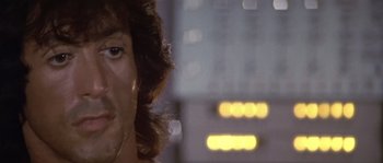 Movie still from “Rambo: First Blood Part II” (1985), directed by George P. Cosmatos – A man's face in front of a building; Close Up shot, Low angle