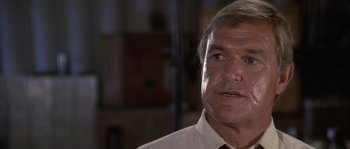 Movie still from “Rambo: First Blood Part II” (1985), directed by George P. Cosmatos – An older man in a white dress shirt and tie; Close Up shot, Low angle