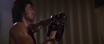 Movie still from “Rambo: First Blood Part II” (1985), directed by George P. Cosmatos – A man is holding a video camera in his hand; Close Up shot, Low angle