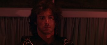 Movie still from “Rambo: First Blood Part II” (1985), directed by George P. Cosmatos – A person wearing a black shirt; Close Up shot, Over the shoulder angle