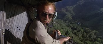Movie still from “Rambo: First Blood Part II” (1985), directed by George P. Cosmatos – A man in a helicopter flying over a forest; Medium shot, Low angle