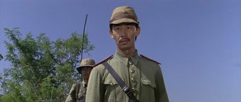 Movie still from “Rambo: First Blood Part II” (1985), directed by George P. Cosmatos – A man in a military uniform standing next to another man in a military uniform; Close Up shot, Low angle