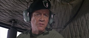 Movie still from “Rambo: First Blood Part II” (1985), directed by George P. Cosmatos – An older man wearing headphones while wearing an army uniform; Close Up shot, Over the shoulder angle