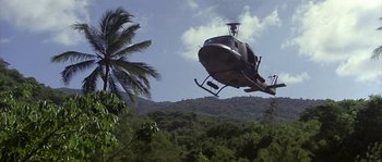 Movie still from “Rambo: First Blood Part II” (1985), directed by George P. Cosmatos – A helicopter flying over a lush green hillside; Extreme Wide shot, Low angle