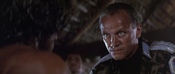 Movie still from “Rambo: First Blood Part II” (1985), directed by George P. Cosmatos – A man's face in a dark room; Close Up shot, Low angle