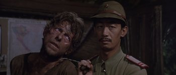 Movie still from “Rambo: First Blood Part II” (1985), directed by George P. Cosmatos – Two men in military uniforms are posing for a picture; Close Up shot, Over the shoulder angle