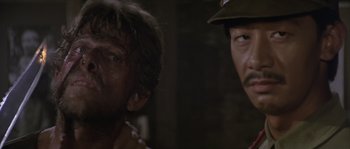 Movie still from “Rambo: First Blood Part II” (1985), directed by George P. Cosmatos – Two men in the dark looking at each other; Close Up shot, Over the shoulder angle