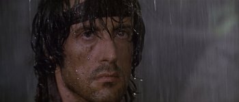 Movie still from “Rambo: First Blood Part II” (1985), directed by George P. Cosmatos – A man with wet hair is looking at the camera; Close Up shot, Low angle