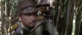 Movie still from “Rambo: First Blood Part II” (1985), directed by George P. Cosmatos – A man in a hat is holding a box of candy; Close Up shot, High angle