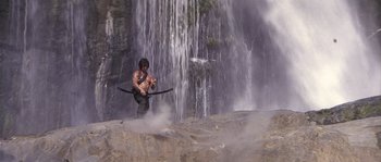 Movie still from “Rambo: First Blood Part II” (1985), directed by George P. Cosmatos – A man holding a fishing rod in front of a waterfall; Wide shot, Low angle