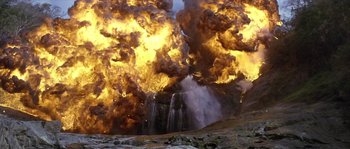 Movie still from “Rambo: First Blood Part II” (1985), directed by George P. Cosmatos – An explosion is seen in the background of a waterfall; Extreme Wide shot, Low angle