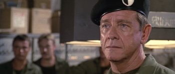 Movie still from “Rambo: First Blood Part II” (1985), directed by George P. Cosmatos – An older man wearing a military uniform and a hat; Close Up shot, Over the shoulder angle