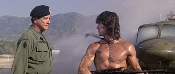 Movie still from “Rambo: First Blood Part II” (1985), directed by George P. Cosmatos – A statue of a man with a gun in his hand; Medium shot, Over the shoulder angle