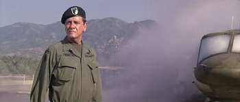 Movie still from “Rambo: First Blood Part II” (1985), directed by George P. Cosmatos – A man in a military uniform standing in front of a mountain; Medium shot, Low angle