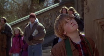 Movie still from “Ransom” (1996), directed by Ron Howard – A young boy with his head tilted to the side looking up; Medium shot, Low angle
