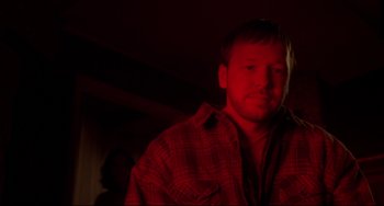 Movie still from “Ransom” (1996), directed by Ron Howard – A man in a plaid shirt is standing in the dark; Close Up shot, Over the shoulder angle