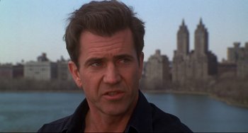 Movie still from “Ransom” (1996), directed by Ron Howard – A person wearing a black shirt near a body of water; Close Up shot, Over the shoulder angle