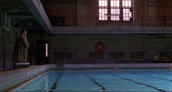 Movie still from “Ransom” (1996), directed by Ron Howard – A swimming pool in a building with a lifesaver on the wall; Extreme Wide shot, High angle