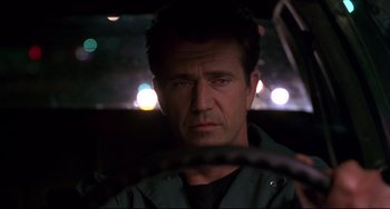 Movie still from “Ransom” (1996), directed by Ron Howard – A person driving a car at night; Close Up shot, Low angle