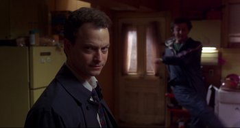 Movie still from “Ransom” (1996), directed by Ron Howard – A man wearing a suit and tie in a room; Medium shot, Over the shoulder angle