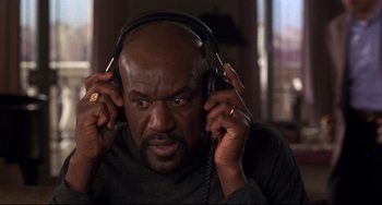 Movie still from “Ransom” (1996), directed by Ron Howard – A man with a beard is listening to headphones; Close Up shot, Low angle