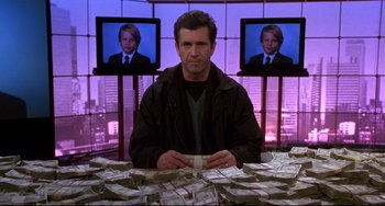 Movie still from “Ransom” (1996), directed by Ron Howard – A man sitting in front of a bunch of money; Medium shot, Low angle