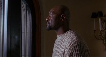 Movie still from “Ransom” (1996), directed by Ron Howard – A man in a sweater looking out of a window; Medium shot, Low angle