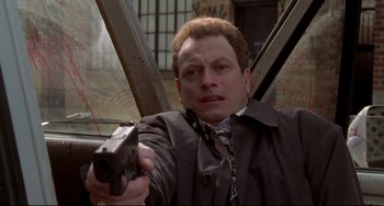 Movie still from “Ransom” (1996), directed by Ron Howard – A man holding a gun while standing in front of a window; Close Up shot, Low angle