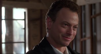 Movie still from “Ransom” (1996), directed by Ron Howard – A person wearing a suit and smiling; Close Up shot, Over the shoulder angle